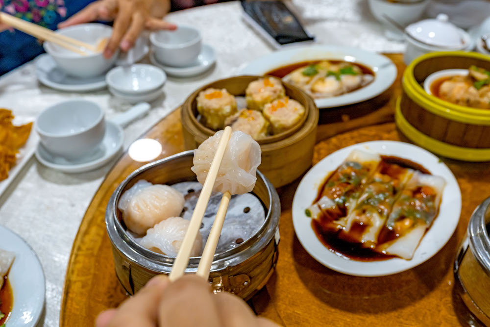 People using chopsticks and having Hong Kong dimsum in restaurant